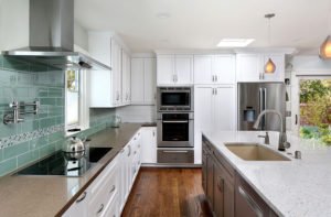 A Mountain View kitchen offers a chic, beachy feel with white cabinetry and a seafoam green backsplash.
