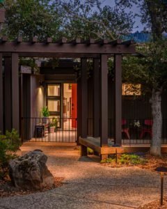 A pergola with a bench seat establishes an entryway to this Portola Valley home.
