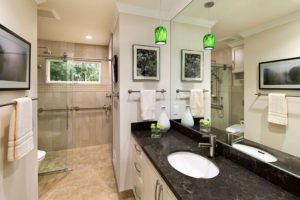 A contemporary universal design bathroom features a curbless shower and brushed silver railings.