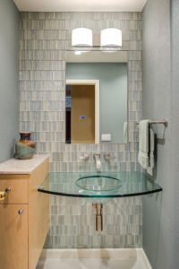 A contemporary Cupertino bathroom features a full tiled backsplash and glass vanity.