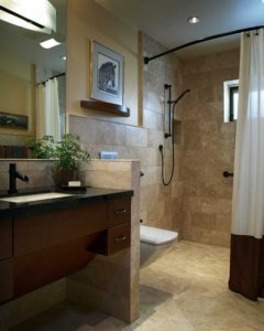 A universal design bathroom with a curbless shower with a curved curtain rod, a tankless wall-mounted toilet, and wooden roll-under vanity.