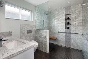 A modern, gray universal design bathroom features a curbless shower and tile details.