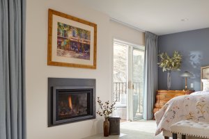 This primary bedroom in os Gatos is the perfect retreat with a fireplace and private balcony.